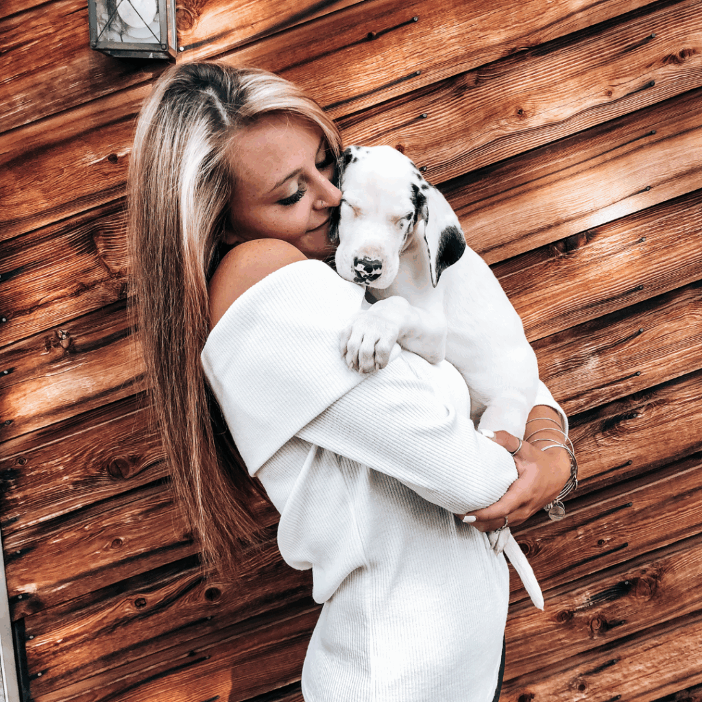 Haley holding her new Great Dane puppy, Dymond, against a cedar wall